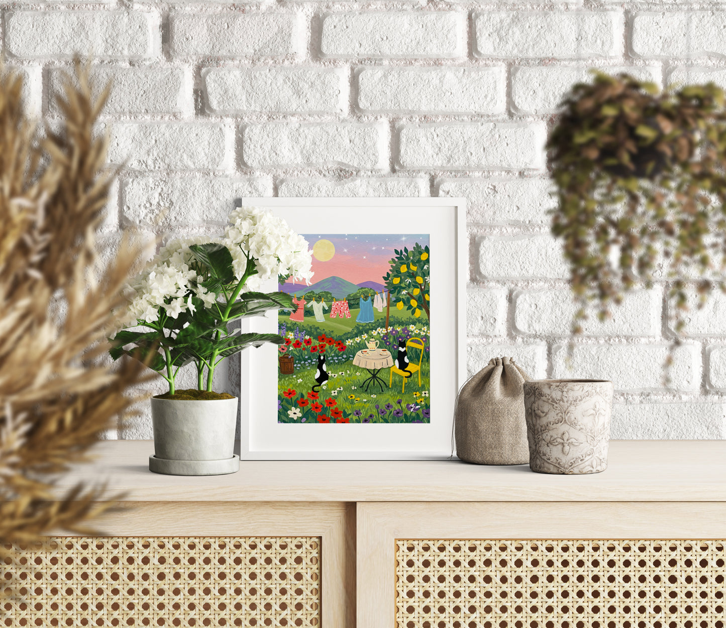 Two cats having tea at sunset with a laundry line in the background and a whimsical landscape scene perfect for cozy home wall decor
